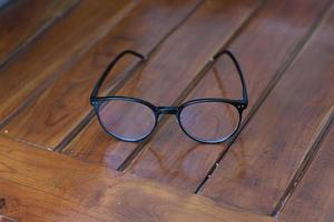 a close up of eyeglasses with black frames isolated natural patterned wooden background. photo