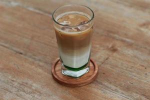 a glass of pandan coffee latte served cold on the table. photo