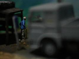 a close up of a miniature figure of an old man talking to other people in an old building by the side of the road. photo