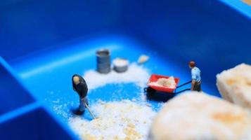 a miniature figure of a worker tidying a peanut cake sprinkled with powdered white sugar. concept of workers in the food industry. photo