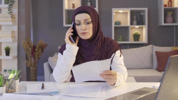 frustrato attività commerciale donna nel hijab. casa ufficio. musulmano attività commerciale donna nel hijab parlando su il Telefono e ottenere arrabbiato. video