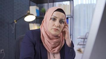 Office worker in hijab is thoughtful. Muslim business woman works in the office and is thoughtful. video