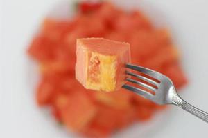 a close up of sliced papaya stabbed with a fork photo