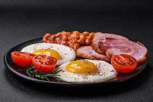 Delicious nutritious English breakfast with fried eggs and tomatoes photo