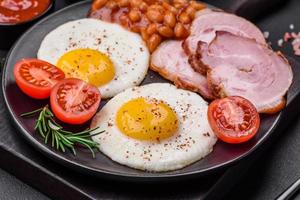 Delicious nutritious English breakfast with fried eggs and tomatoes photo