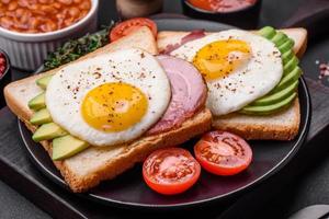 delicioso nutritivo Inglés desayuno con frito huevos, Tomates y aguacate foto
