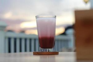 a glass of red velvet latte served cold on the table. photo