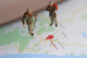 miniatura figura de un explorador posando en un digital mapa vía un móvil teléfono foto