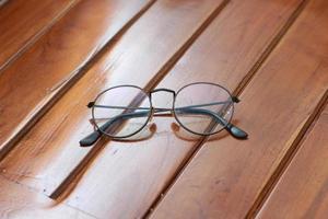 a close up of eyeglasses with black frames isolated natural patterned wooden background. photo