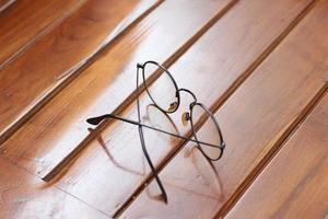 a close up of eyeglasses with black frames isolated natural patterned wooden background. photo