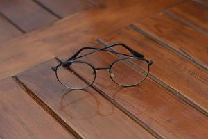 a close up of eyeglasses with black frames isolated natural patterned wooden background. photo