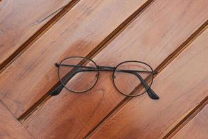 a close up of eyeglasses with black frames isolated natural patterned wooden background. photo