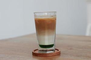 a glass of pandan coffee latte served cold on the table. photo