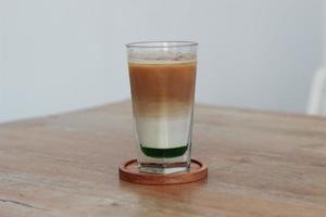 a glass of pandan coffee latte served cold on the table. photo