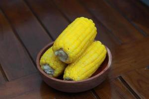 a close up of corn on the cob served in a wooden bowl. photo