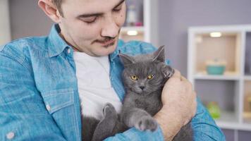 Close-up portrait of happy man and his cat. The man is holding a gray cat happily in his arms with a strong hug.