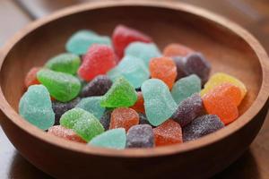 a close up of gummy candies of various colors and fruit flavors served in a wooden bowl. photo