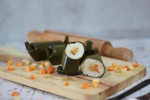 un cerca arriba de mucho tiempo tradicional comida desde Indonesia originario desde arroz lleno con vegetales o carne y envuelto en plátano hojas. indonesio tradicional comida foto concepto.