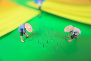 miniature figure of farmers growing crops in the form of staples on green paper. Concept of agriculture photo. photo
