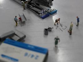 Miniature figures of workers working in a staples production factory. photo