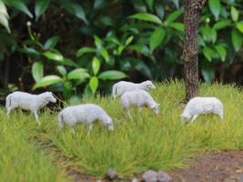 a close up of miniature figures of a herd of goats eating grass. Animal farm photo concept.