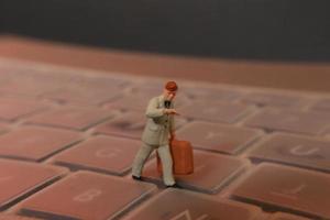 un miniatura figura de un oficina trabajador que lleva un maletín caminando Entre el teclados. foto