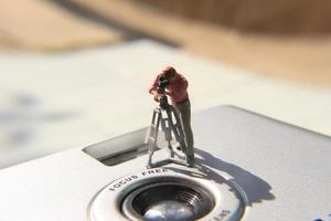 miniatura figura de un camarógrafo grabación en un término análogo cámara. foto