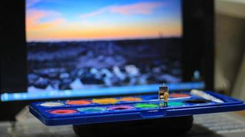 a miniature figure of a painter painting a landscape on watercolors. artist concept. photo