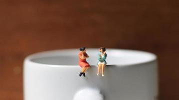 Miniature figures of 2 women talking over glasses. discussion concept. photo