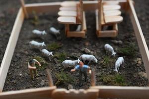 A close up of miniature figure of a goat herder feeding in a wooden cage. Shepherd concept. photo