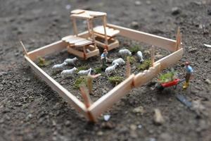 A close up of miniature figure of a goat herder feeding in a wooden cage. Shepherd concept. photo