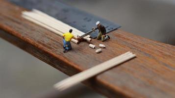Miniature figure of a worker cutting toothpicks. carpenter activity photo concept.