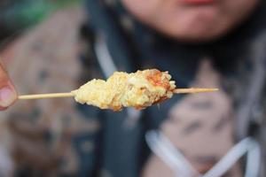 photo of chicken satay coated with fried egg and served with red chili sauce. Indonesian food called Sate Taichan. Food concept photo.