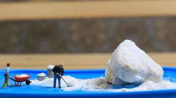 a miniature figure of a worker tidying a peanut cake sprinkled with powdered white sugar. concept of workers in the food industry. photo
