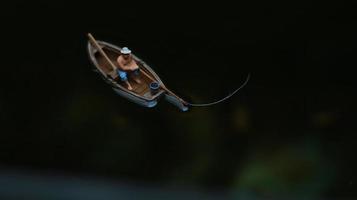 miniature figure of a fisherman fishing on a lake in a small boat. photo