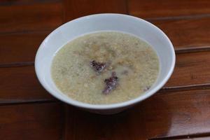 a close up of a bowl of green bean porridge and black sticky rice doused in coconut milk photo