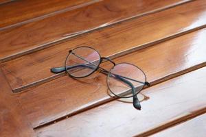 a close up of eyeglasses with black frames isolated natural patterned wooden background. photo