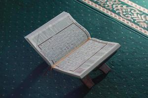 un cerca arriba de el santo libro Al Quran en un verde oración alfombra. islámico foto concepto.