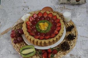 big fruit pie with toppings of strawberries, grapes, kiwi and pineapple. savory, sweet and fresh. Food concept photo. photo