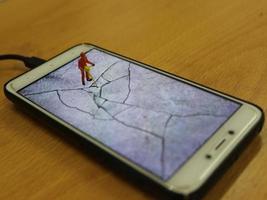 a miniature figure of a highway worker breaking a cell phone screen. photo