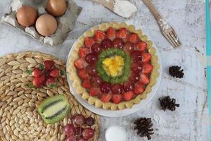 grande Fruta tarta con coberturas de fresas, uvas, kiwi y piña. sabroso, dulce y fresco. comida concepto foto. foto