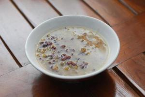 a close up of a bowl of green bean porridge and black sticky rice doused in coconut milk photo