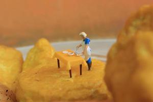 miniatura figura de un madre Cocinando en amarillo tofu. foto