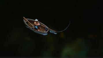 miniature figure of a fisherman fishing on a lake in a small boat. photo