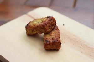 a close up of fried tempeh on a wooden cutting board photo