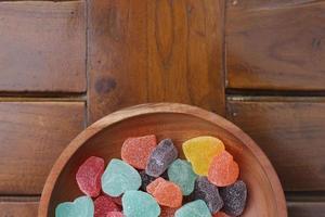 a close up of gummy candies of various colors and fruit flavors served in a wooden bowl. photo