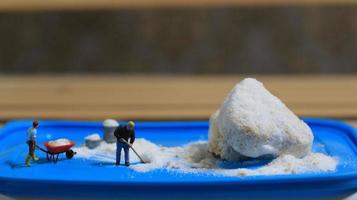 a miniature figure of a worker tidying a peanut cake sprinkled with powdered white sugar. concept of workers in the food industry. photo