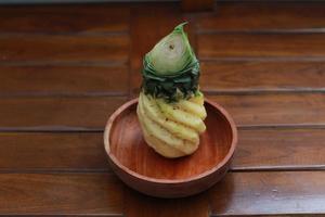 a close up of a peeled pineapple on a wooden bowl. fruit photo concept.