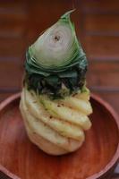 a close up of a peeled pineapple on a wooden bowl. fruit photo concept.