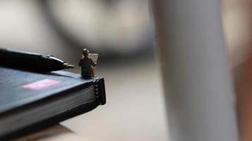 a view of miniature figure reading a newspaper on a book. photo